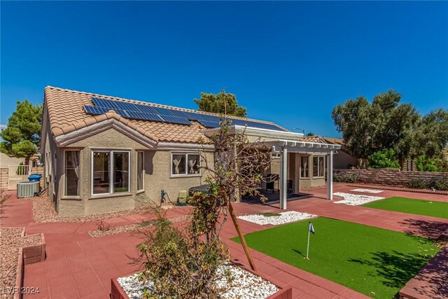8705 Villa Ridge Dr, Las Vegas, NV 89134 - back of house with an area to practice putting, a patio area, a tiled roof, and roof mounted solar panels