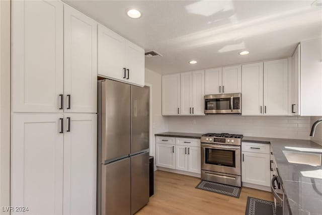 8705 Villa Ridge Dr, Las Vegas, NV 89134 - kitchen featuring stainless steel appliances, white cabinetry, light wood finished floors, backsplash, and recessed lighting