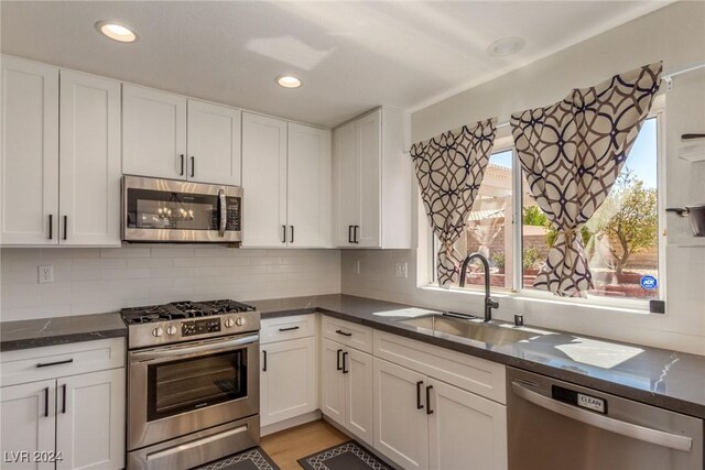 8705 Villa Ridge Dr, Las Vegas, NV 89134 - kitchen featuring appliances with stainless steel finishes, white cabinets, decorative backsplash, dark stone counters, and recessed lighting