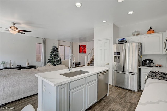 kitchen with appliances with stainless steel finishes, dark hardwood / wood-style flooring, a kitchen island with sink, sink, and white cabinets