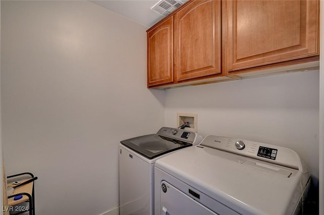 laundry room featuring washing machine and clothes dryer and cabinets