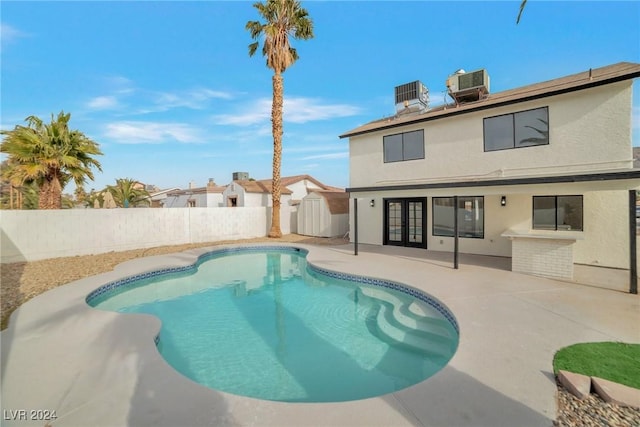 view of pool featuring central air condition unit, a patio area, a shed, and french doors