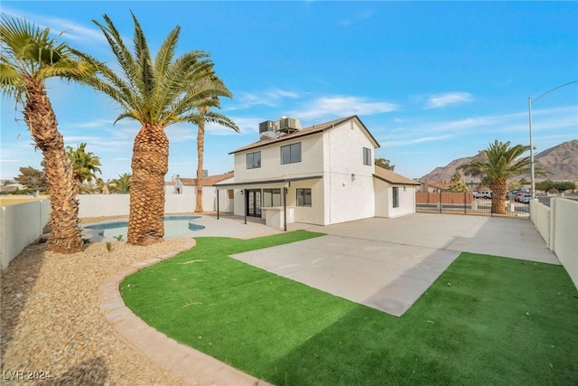 rear view of house featuring a patio area, a fenced in pool, a yard, and a mountain view