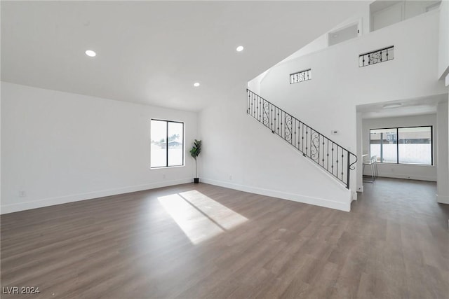 unfurnished living room with high vaulted ceiling and dark hardwood / wood-style flooring