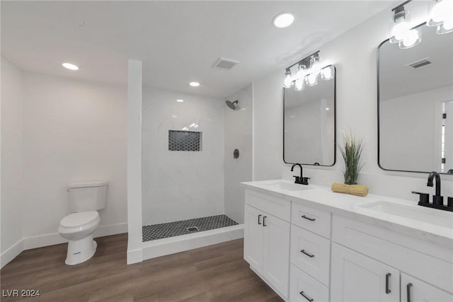 bathroom featuring a tile shower, hardwood / wood-style flooring, toilet, and vanity