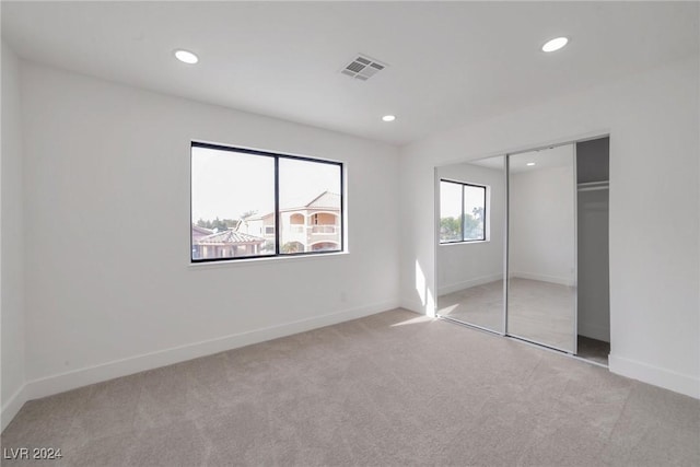 unfurnished bedroom featuring a closet and light carpet