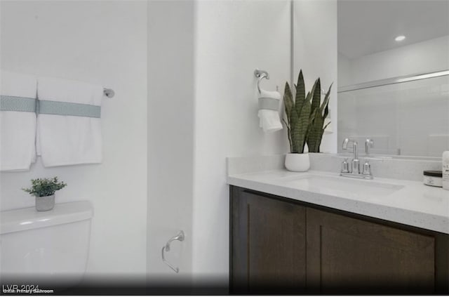 bathroom with walk in shower, vanity, and toilet