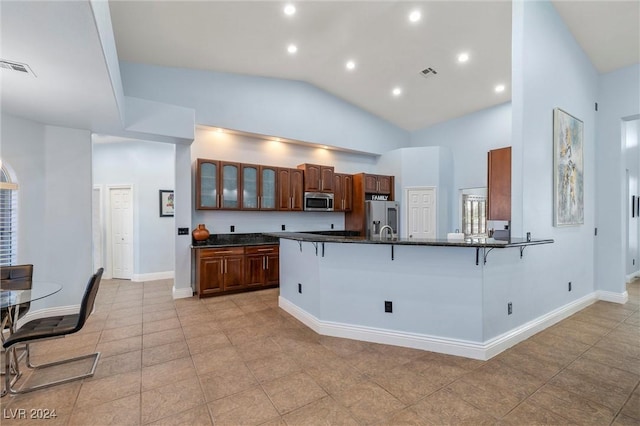 kitchen with high vaulted ceiling, kitchen peninsula, a kitchen breakfast bar, and stainless steel appliances