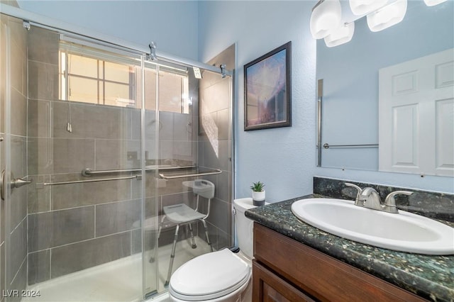 bathroom featuring a shower with shower door, toilet, and vanity