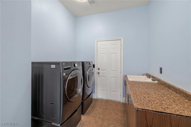 washroom featuring cabinets, light tile patterned floors, washing machine and clothes dryer, and sink