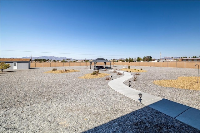 view of yard featuring a gazebo, a mountain view, and a storage unit