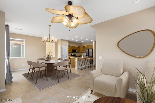 dining space with light tile patterned floors and ceiling fan with notable chandelier