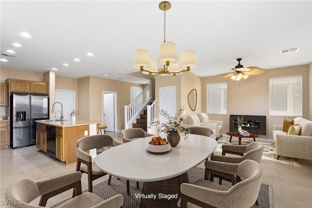 tiled dining space featuring sink and ceiling fan with notable chandelier