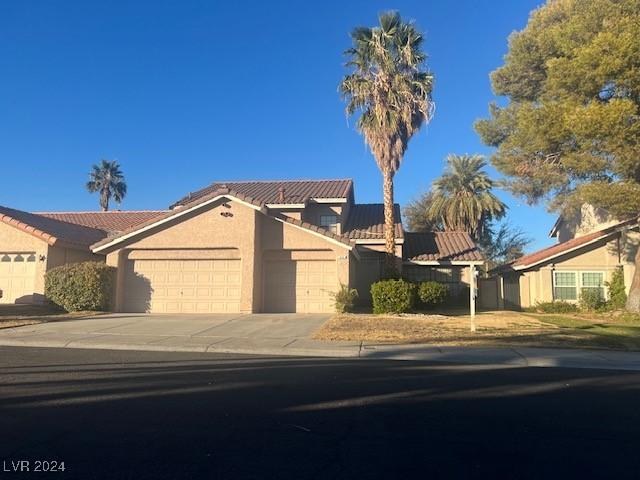 mediterranean / spanish house with a garage, concrete driveway, roof mounted solar panels, and stucco siding