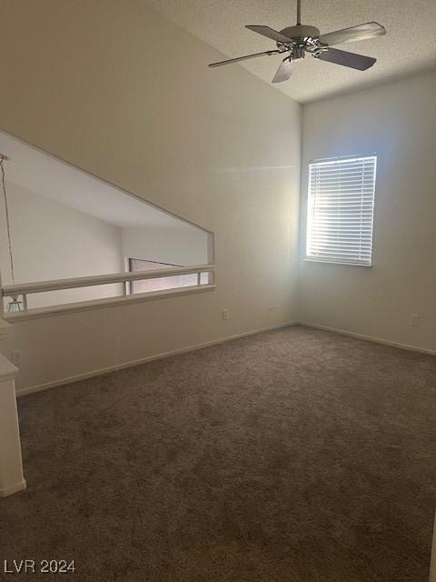 carpeted spare room with lofted ceiling, ceiling fan, baseboards, and a textured ceiling