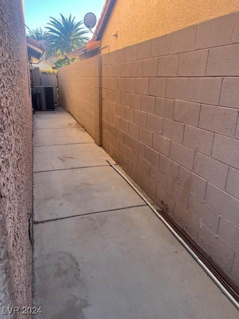 view of property exterior with concrete block siding, fence, and central AC unit