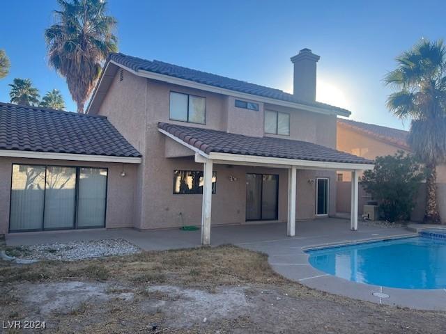 rear view of house with a patio area, a fenced in pool, and stucco siding