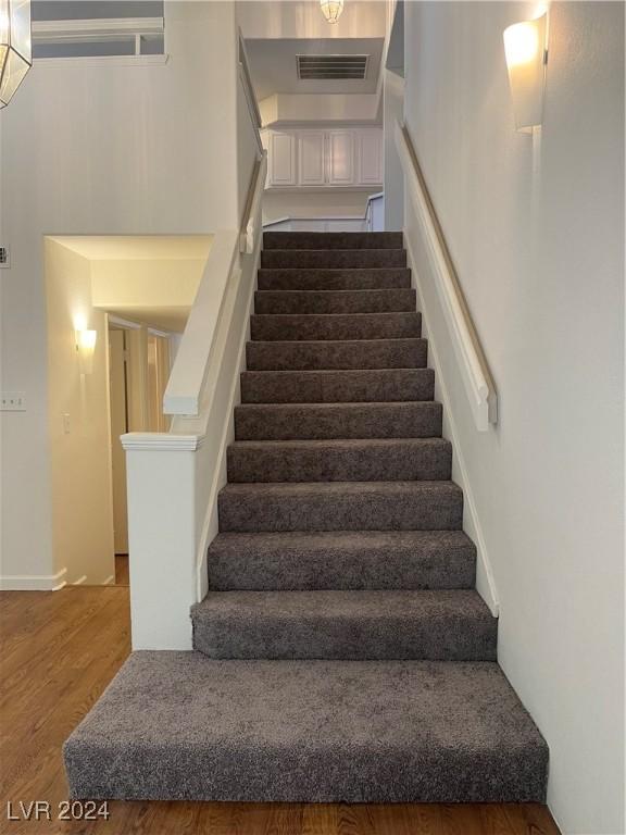 staircase featuring visible vents and wood finished floors