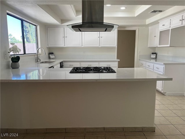 kitchen featuring visible vents, a peninsula, island exhaust hood, gas stovetop, and a sink