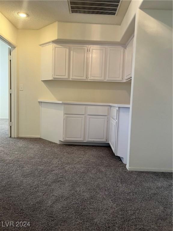 kitchen with visible vents, dark carpet, light countertops, a textured ceiling, and white cabinetry