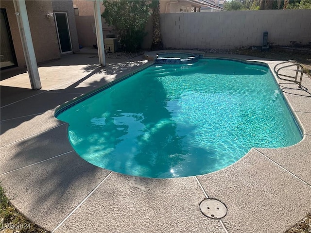 view of swimming pool featuring a patio area, a pool with connected hot tub, and fence