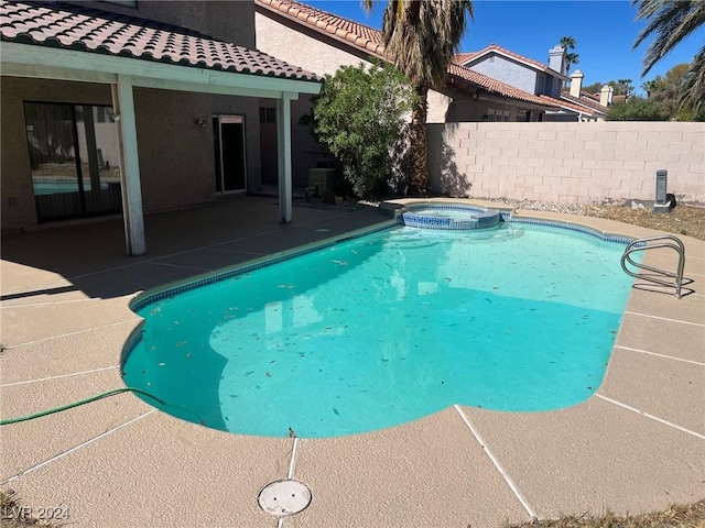 view of swimming pool featuring a patio area, fence, and a pool with connected hot tub