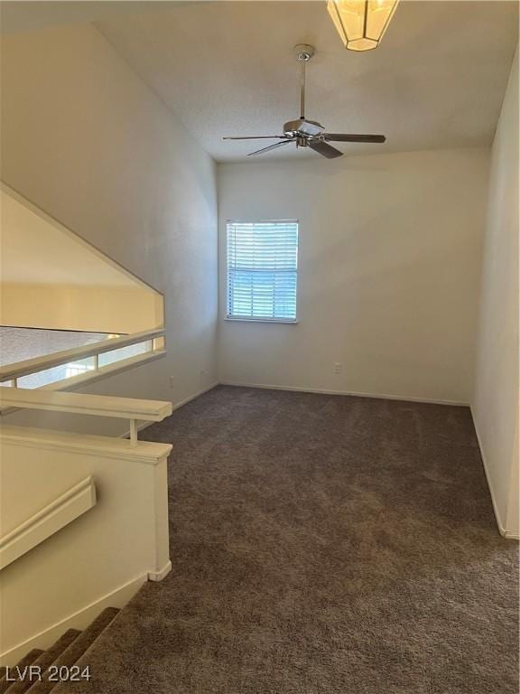 spare room featuring dark carpet and a ceiling fan