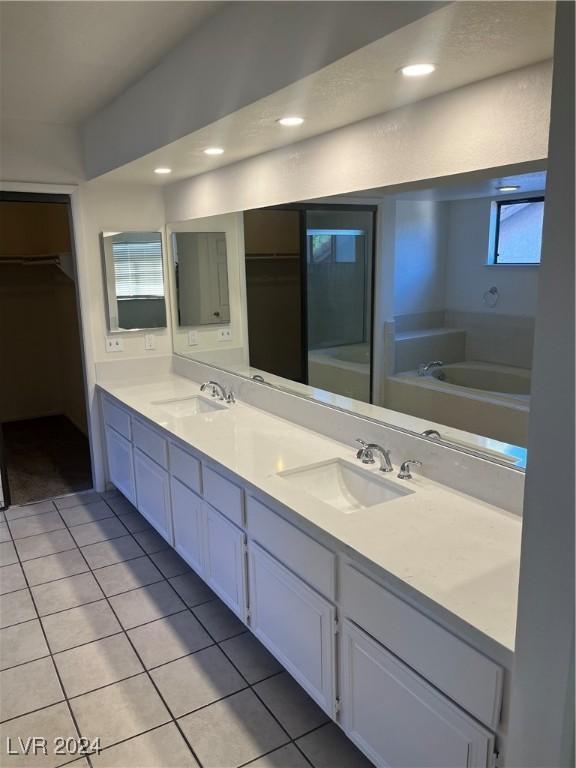 bathroom with double vanity, tile patterned flooring, a sink, and a bath