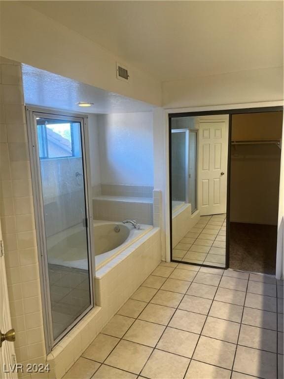 full bath featuring tile patterned flooring, visible vents, a shower stall, a bath, and a walk in closet