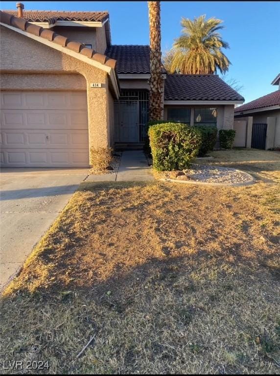 view of front of property with a garage, concrete driveway, a tile roof, and stucco siding