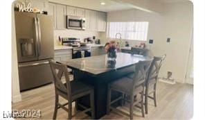 kitchen with a kitchen bar, tasteful backsplash, light hardwood / wood-style flooring, and stainless steel appliances