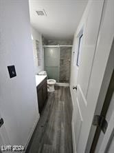 bathroom featuring hardwood / wood-style floors, vanity, toilet, and a shower with door