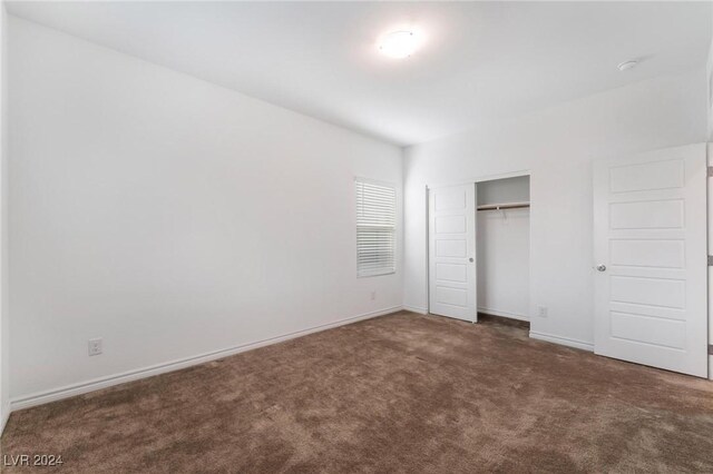 unfurnished bedroom featuring dark colored carpet and a closet