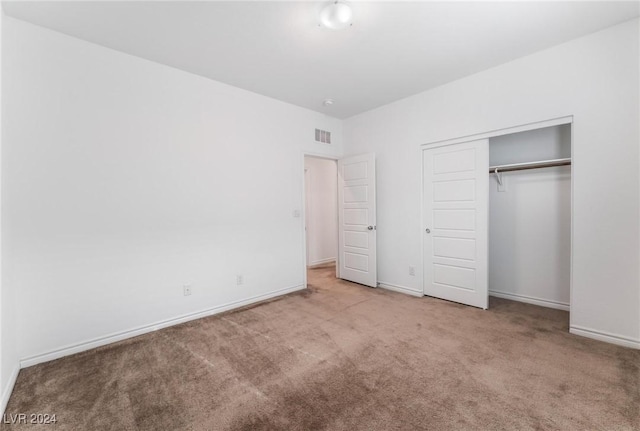 unfurnished bedroom featuring a closet and light colored carpet