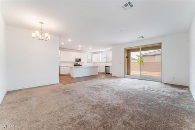 unfurnished living room with light colored carpet and a chandelier