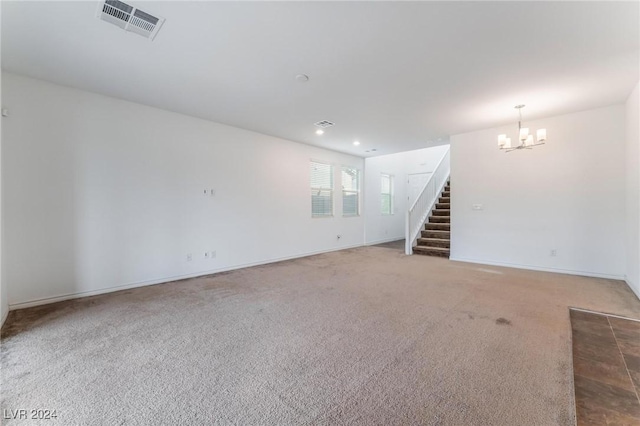 carpeted empty room featuring an inviting chandelier