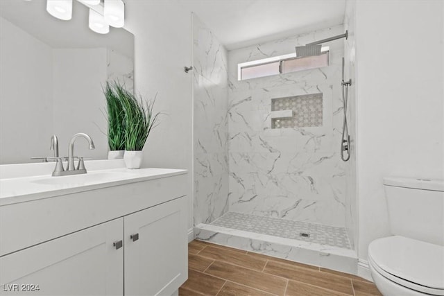 bathroom featuring tiled shower, vanity, and toilet