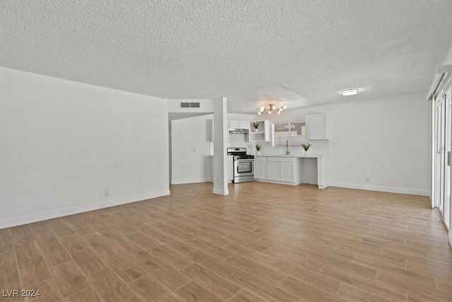 unfurnished living room with light hardwood / wood-style flooring, a textured ceiling, and sink