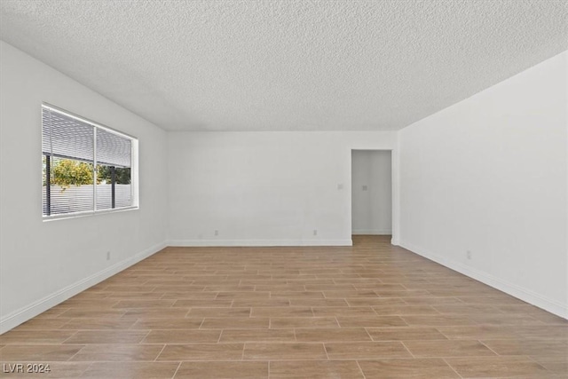 spare room with a textured ceiling and light hardwood / wood-style flooring