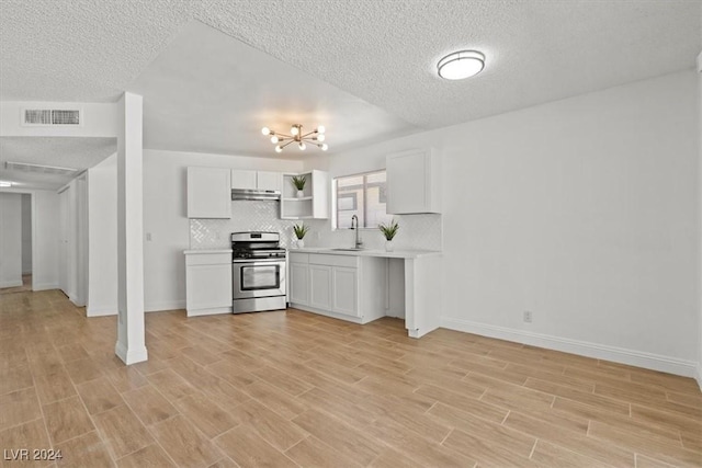 kitchen featuring backsplash, white cabinets, light hardwood / wood-style flooring, gas range, and a textured ceiling