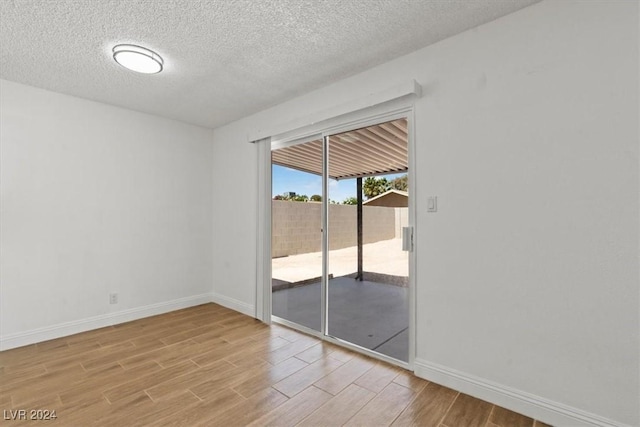 spare room with light hardwood / wood-style floors and a textured ceiling