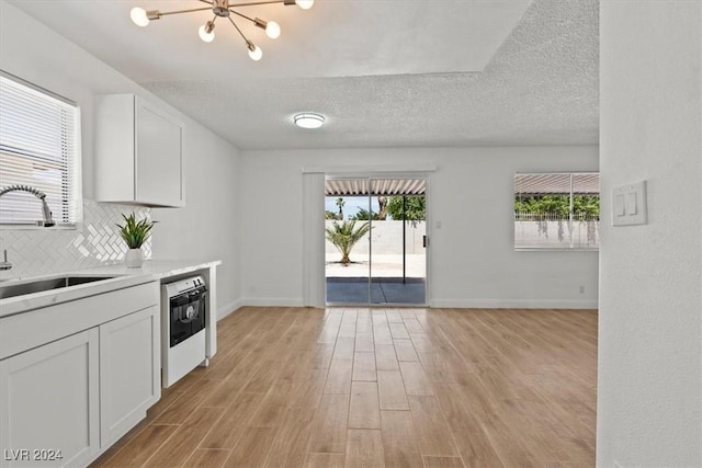 kitchen with white cabinetry, sink, light hardwood / wood-style floors, and a textured ceiling