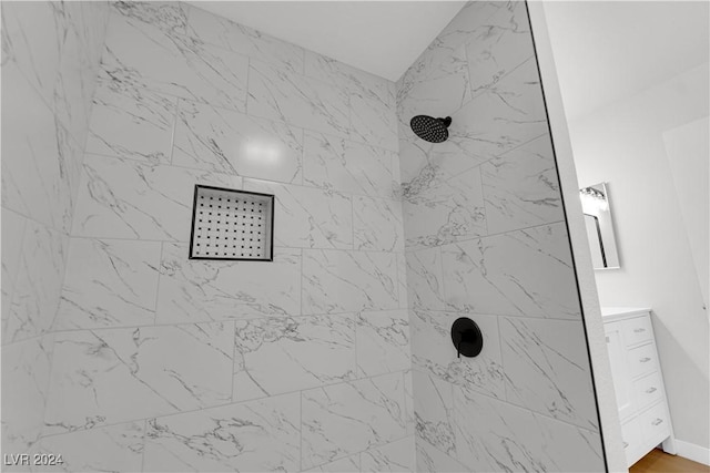 interior details with a tile shower and vanity