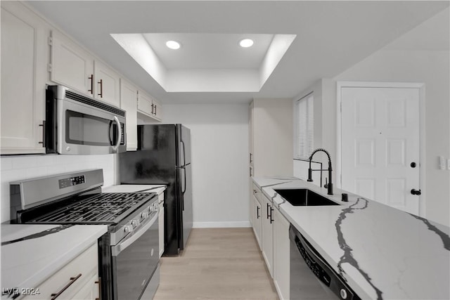 kitchen featuring white cabinets, appliances with stainless steel finishes, light stone countertops, and sink