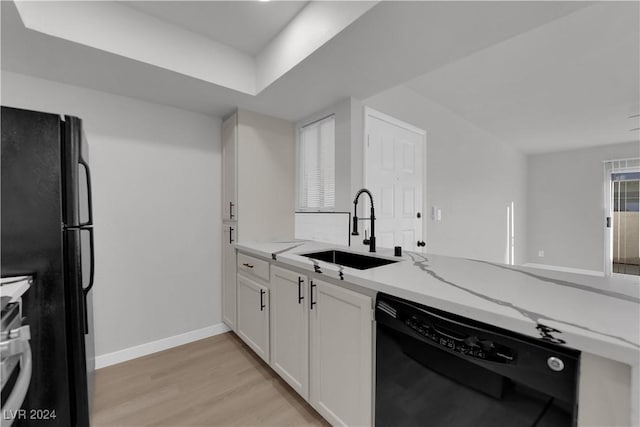 kitchen with light stone counters, sink, black appliances, light hardwood / wood-style flooring, and white cabinets