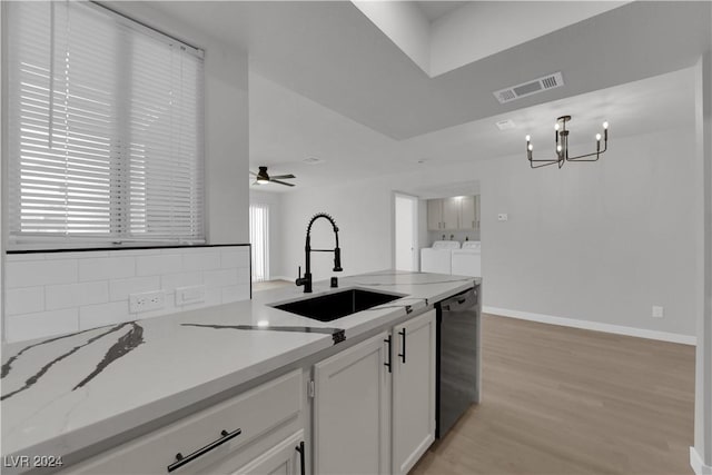 kitchen with washing machine and clothes dryer, white cabinetry, sink, light hardwood / wood-style flooring, and stainless steel dishwasher