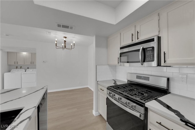 kitchen with white cabinetry, separate washer and dryer, stainless steel appliances, and a chandelier