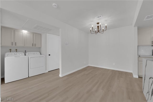 laundry area featuring light hardwood / wood-style floors, cabinets, independent washer and dryer, and an inviting chandelier