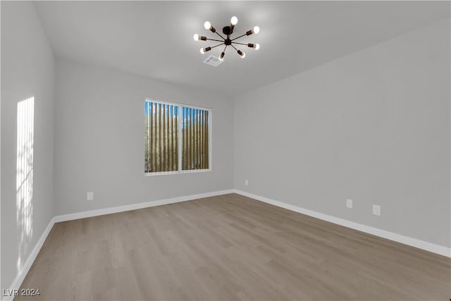 unfurnished room with light wood-type flooring and an inviting chandelier