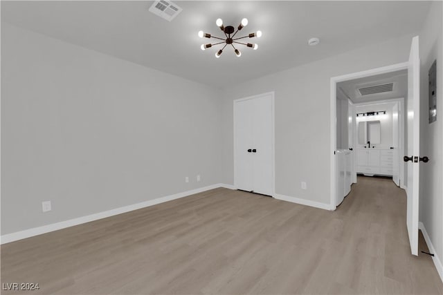 spare room featuring light hardwood / wood-style floors and an inviting chandelier